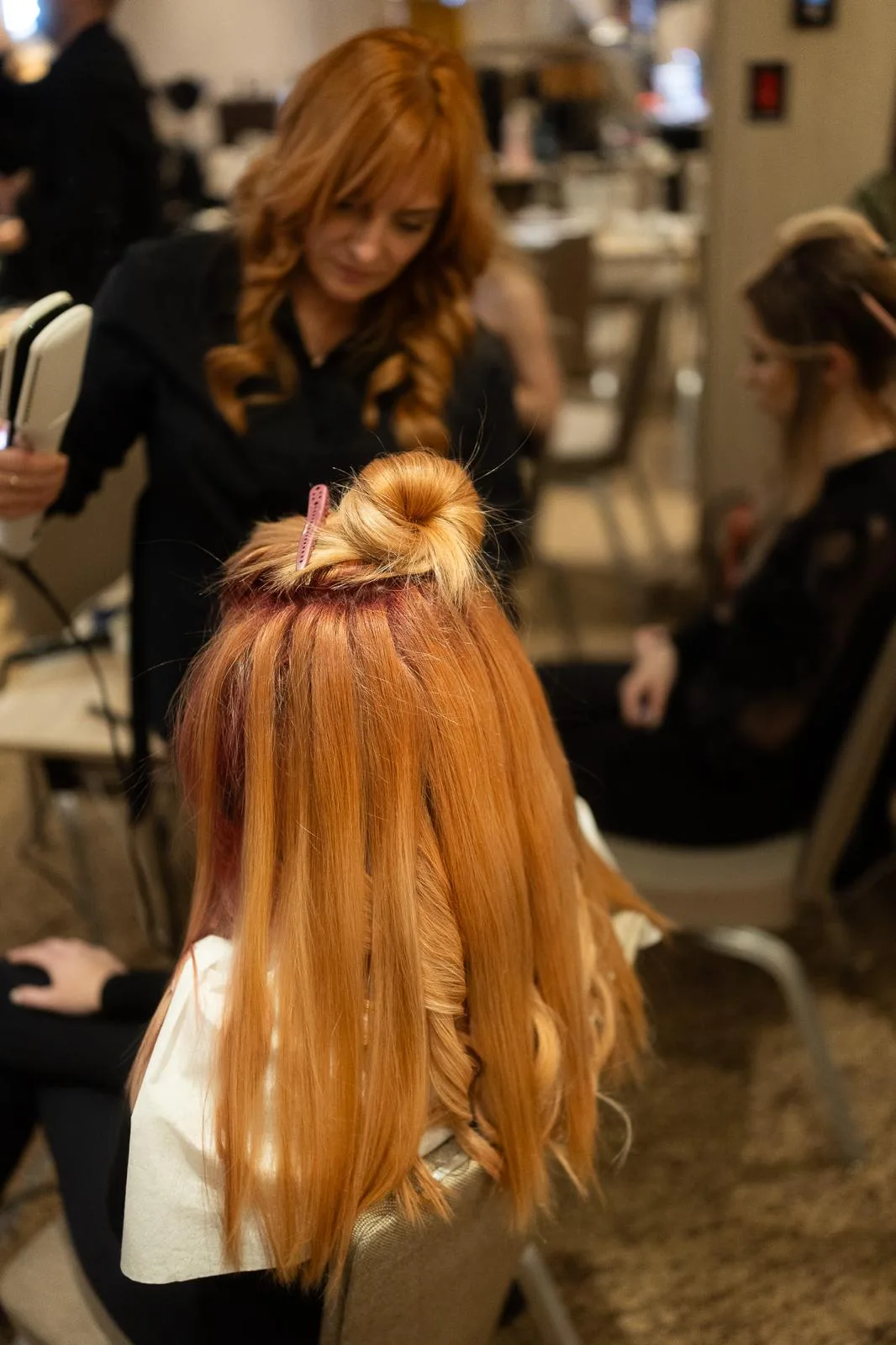 Hairstilist lucrând extensii pe păr lung roșcat